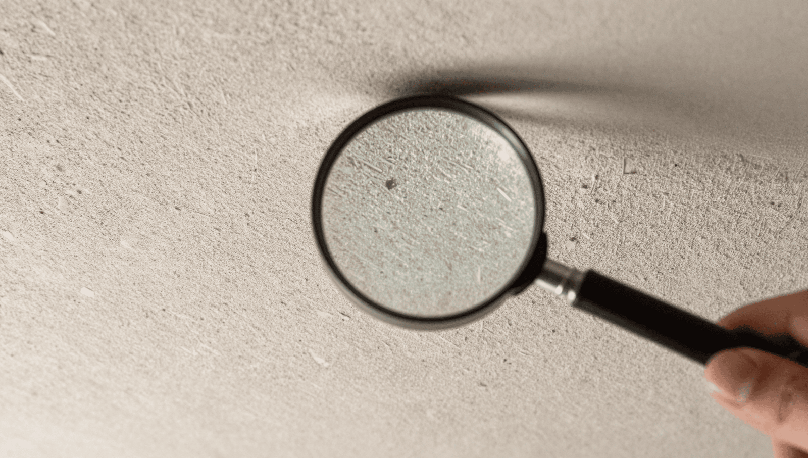 A magnifying glass examining a textured artex ceiling to see how do you know if artex has asbestos.